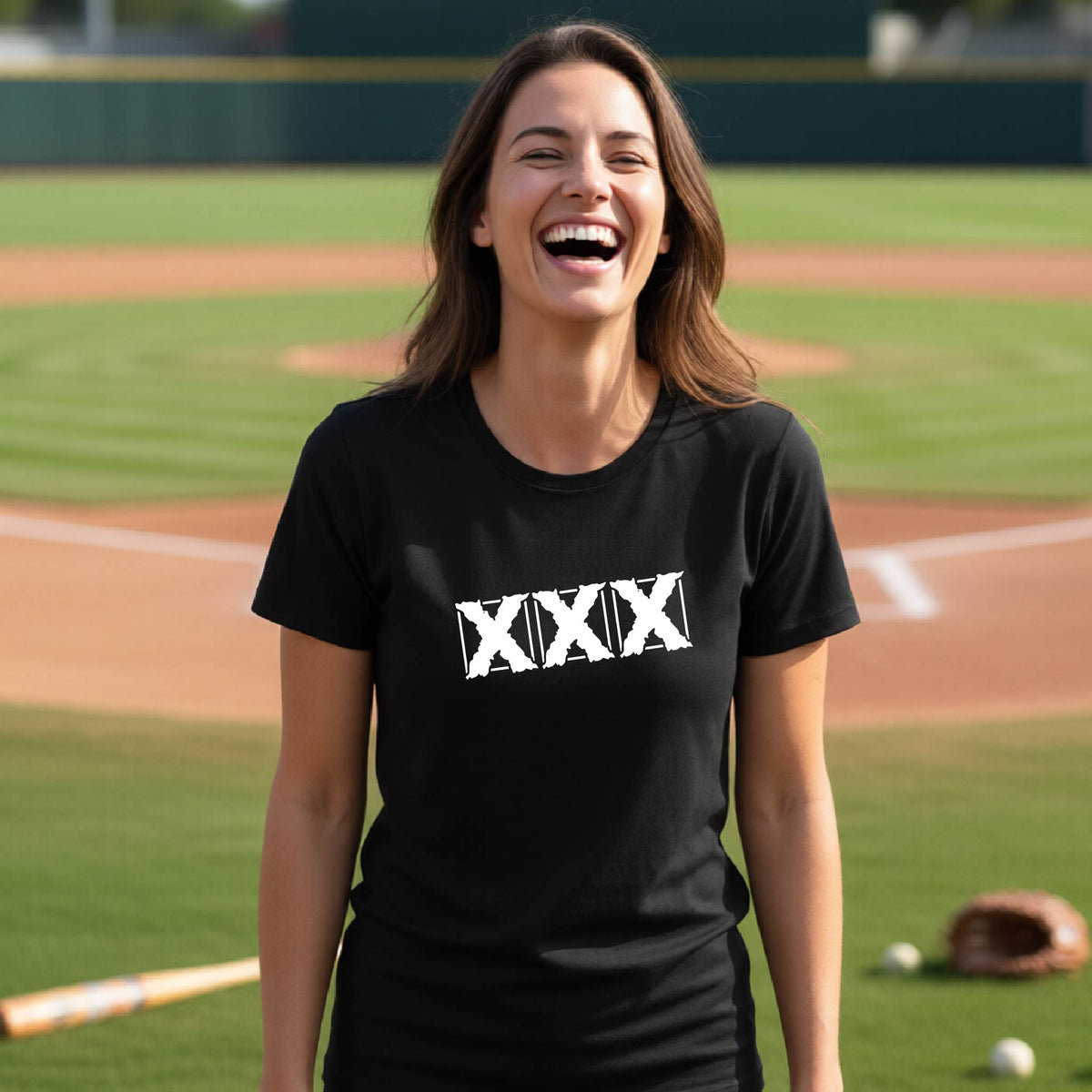 A woman laughing on a baseball field wearing a black t-shirt with a white XXX graphic across the chest.