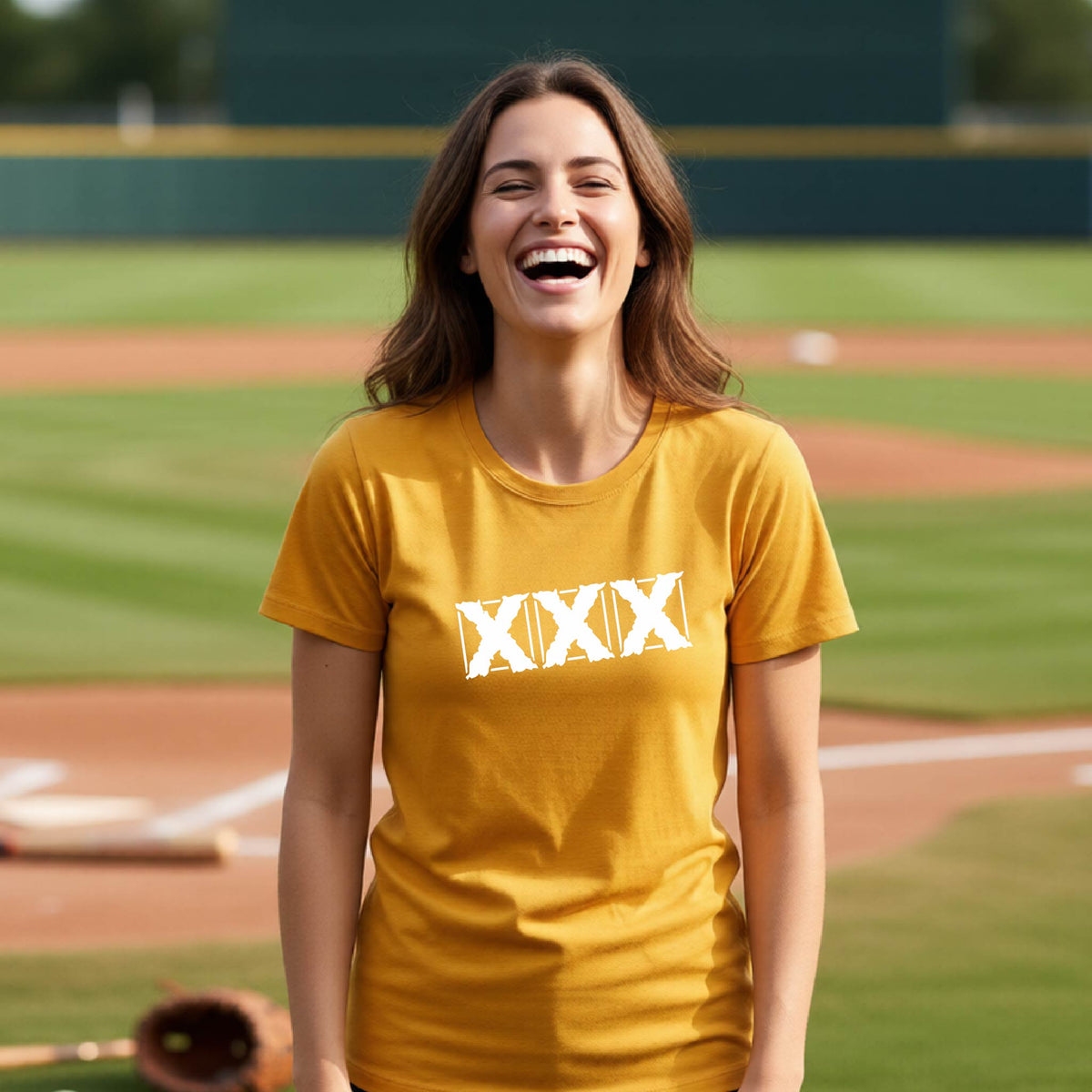 A woman laughing on a baseball field wearing a mustard yellow t-shirt with a white Roman numeral 'XXX' graphic across the chest.