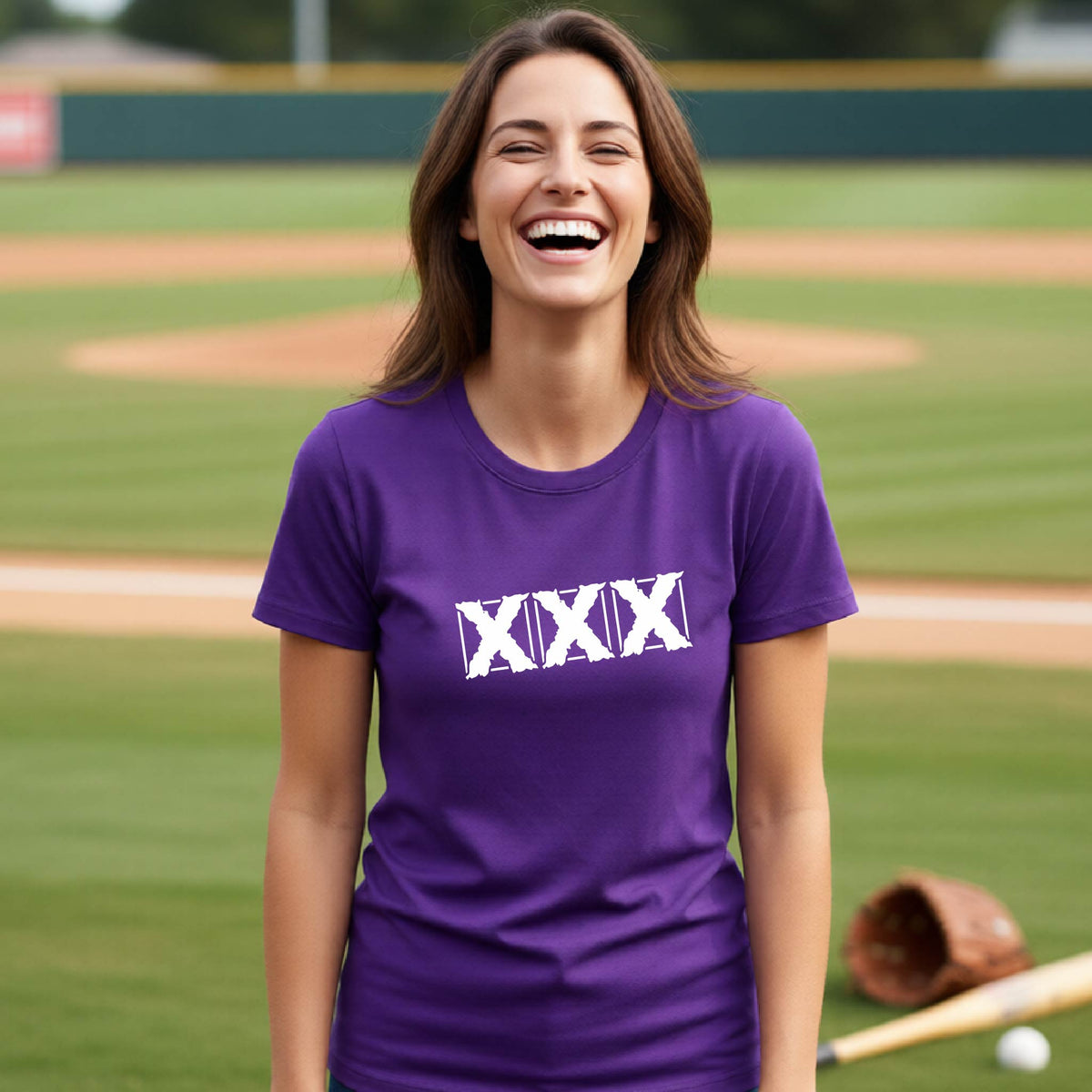 A woman laughing on a baseball field wearing a purple t-shirt with a white Roman numeral 'XXX' graphic across the chest.