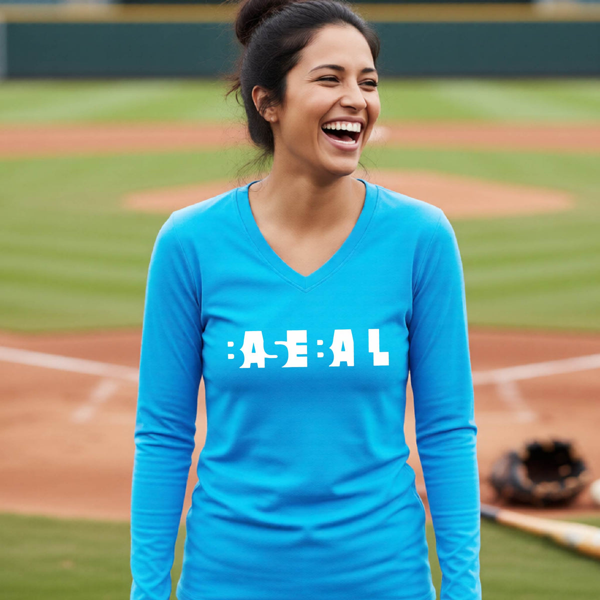 A smiling woman wearing a bright blue long-sleeve athletic shirt with the white text 'BASEBALL' in a cutout design printed across the chest, standing on a baseball field.