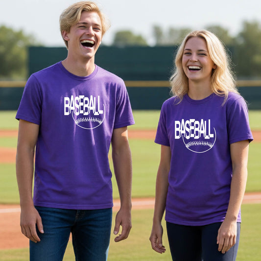 Two young athletes wearing matching purple short-sleeve t-shirts with a white baseball graphic on the chest stands on a baseball field. The shirt features the word 'BASEBALL' in a baseball-style font with a stitched ball design underneath.