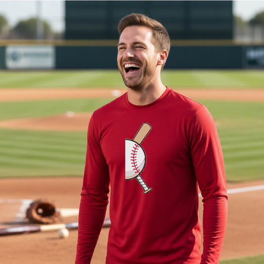 A man smiling in front of a baseball diamond wearing a red long-sleeve t-shirt, with a colorful graphic of a half baseball with a curved bat behind it, printed on the front of the shirt. 