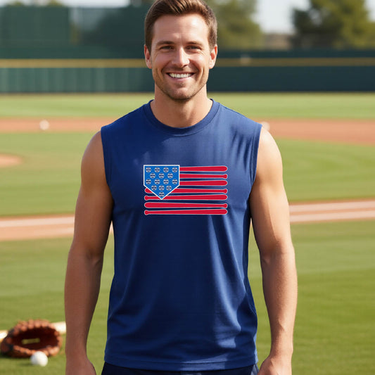 A man smiling in front of a baseball diamond wearing a royal blue sleeveless t-shirt with a colored graphic of an American flag using baseball bats and balls and a home plate, printed on the front.
