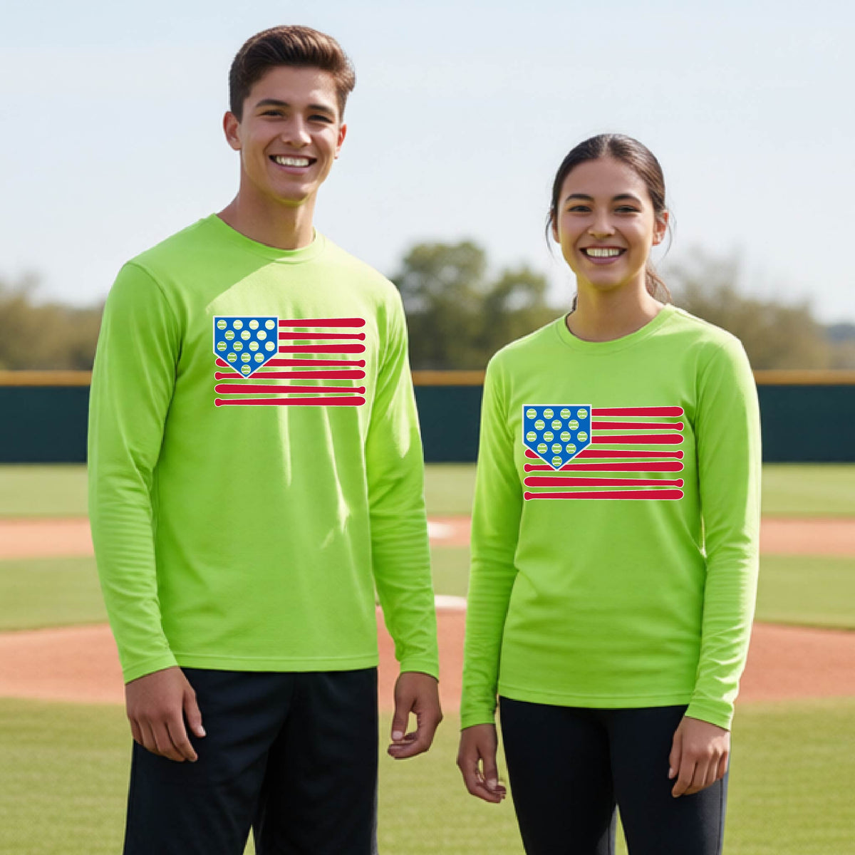 Two young athletes wearing matching shirts smiling in front of a baseball diamond wearing lime green long-sleeve t-shirts with a colored graphic of an American flag using baseball bats and balls and a home plate, printed on the front.