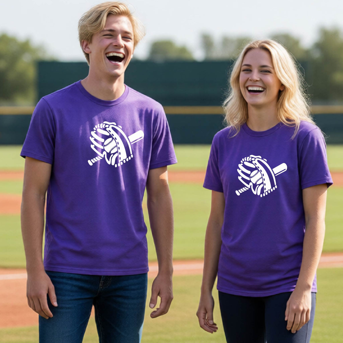 Two young athletes wearing matching shirts, smiling in front of a baseball diamond wearing purple short-sleeve t-shirts with a white graphic of baseball mitt, bat and ball, printed on the front.