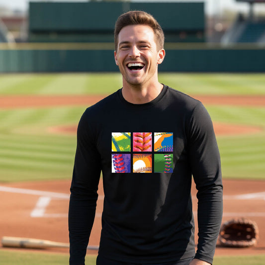 A man smiling in front of a baseball diamond wearing a black long-sleeve t-shirt, with a colorful graphic or 2x3 baseball squares of a baseball, printed on the front.