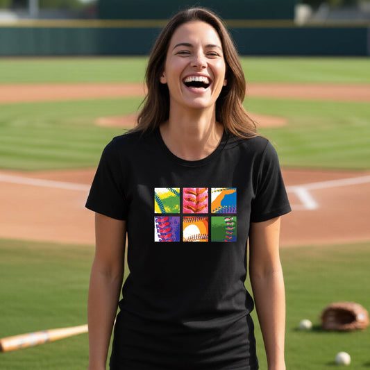 A woman smiling in front of a baseball diamond wearing a black short-sleeve t-shirt, with a colorful graphic or 2x3 baseball squares of a baseball, printed on the front.