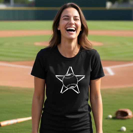 A woman smiling in front of a baseball diamond wearing a black short-sleeve t-shirt, with a white graphic of a star made of baseball bats and a ball in the middle, printed on the front.