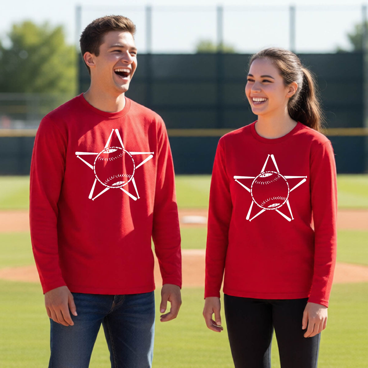 A man smiling in front of a baseball diamond wearing a red long-sleeve t-shirt, with a white graphic of a star made of baseball bats and a ball in the middle, printed on the front.