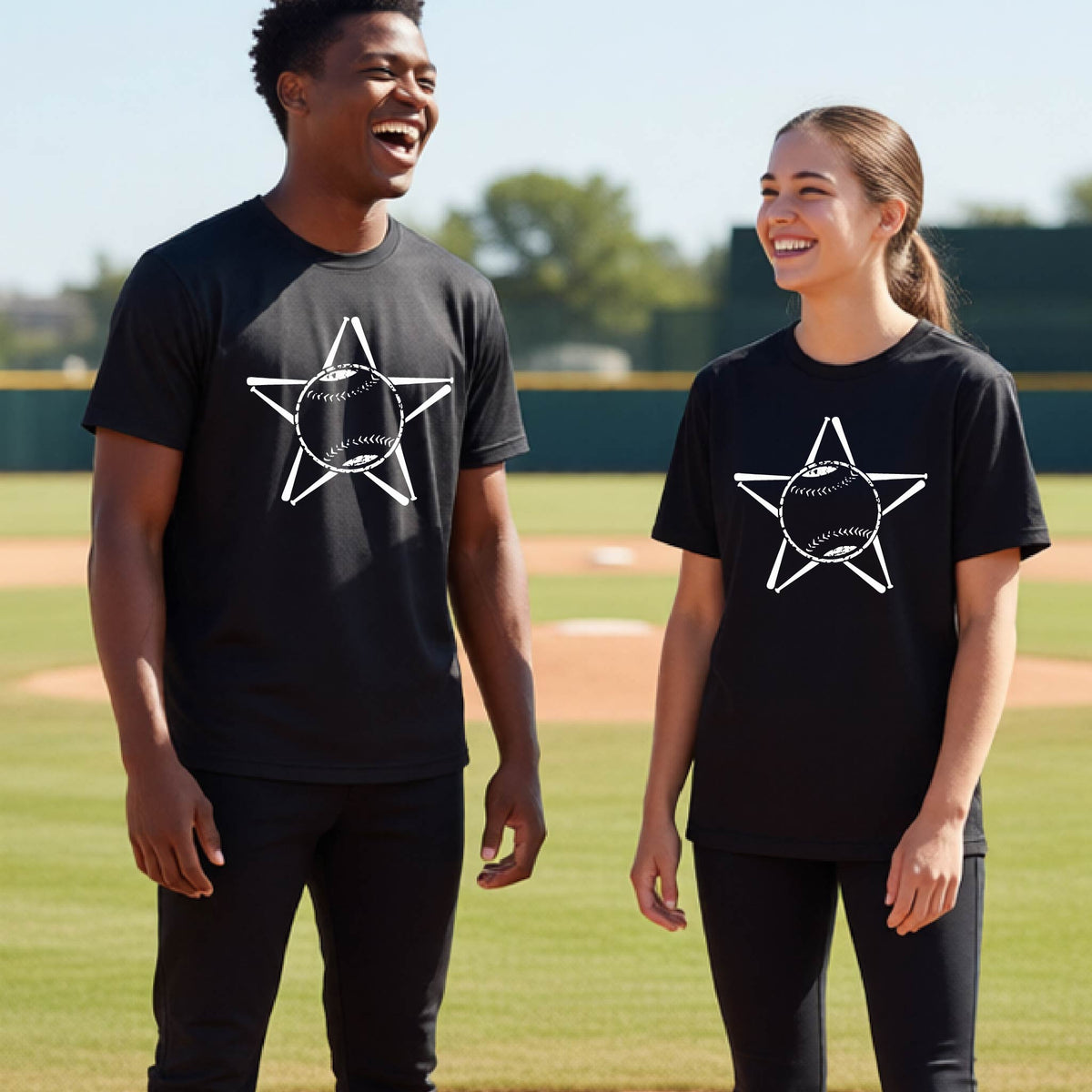 Two youth athletes wearing matching shirts, smiling in front of a baseball diamond wearing black long-sleeve t-shirts with a white graphic of a star made of baseball bats and a ball in the middle, printed on the front.