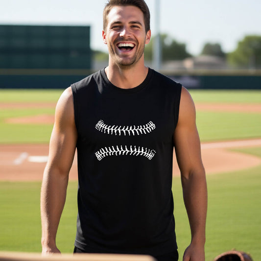 A man smiling in front of a baseball diamond wearing a black sleeveless t-shirt, with a white graphic of baseball stitches, printed on the front.
