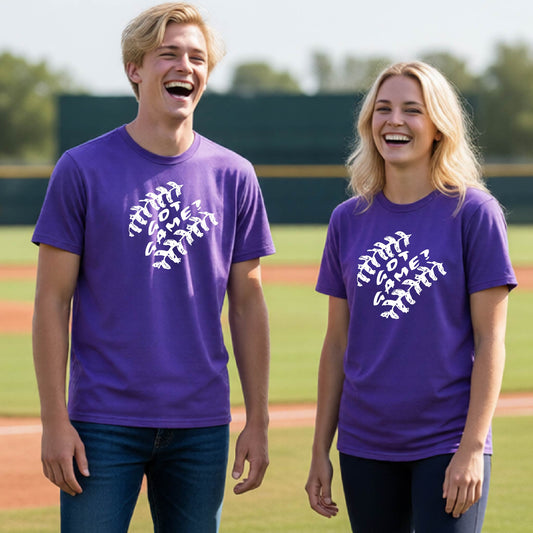 Two youth athletes wearing matching purple short-sleeve t-shirts, smiling in front of a baseball diamond, with a white graphic of baseball stitches and the words ‘GOT GAME’ inside, printed on the front of the shirt.