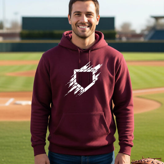 A man smiling in front of a baseball diamond wearing a maroon pullover hoodie, with an artistic white graphic of a sketch of baseball home plate, printed on the front of the shirt.