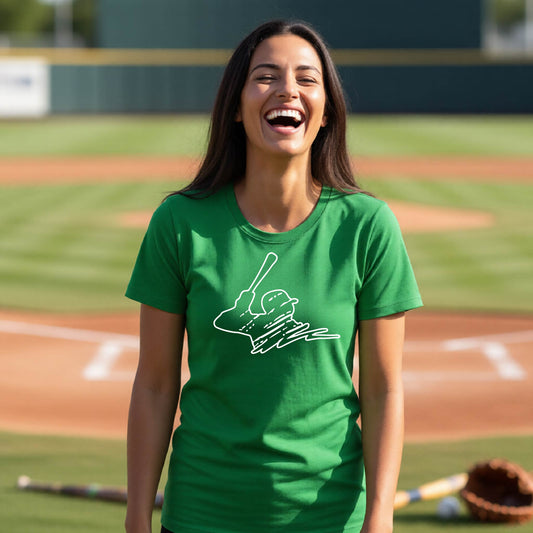 A woman smiling in front of a baseball diamond wearing a green short-sleeve t-shirt, with a white graphic of an outline of a baseball player up to bat, printed on the front.