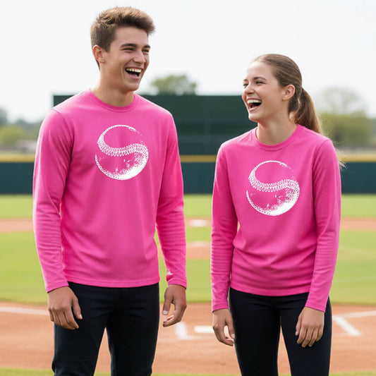Two youth athletes wearing matching shirts, smiling in front of a baseball diamond wearing pink long-sleeve t-shirts, with a white artistic graphic of a baseball, printed on the front.