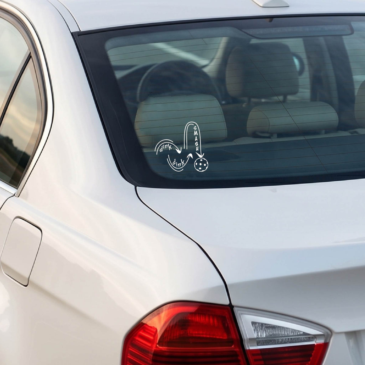 A white vinyl decal of a pickelball logo' DINK DINK SMASH' an a yellow pickleball, applied a vehicle window. 