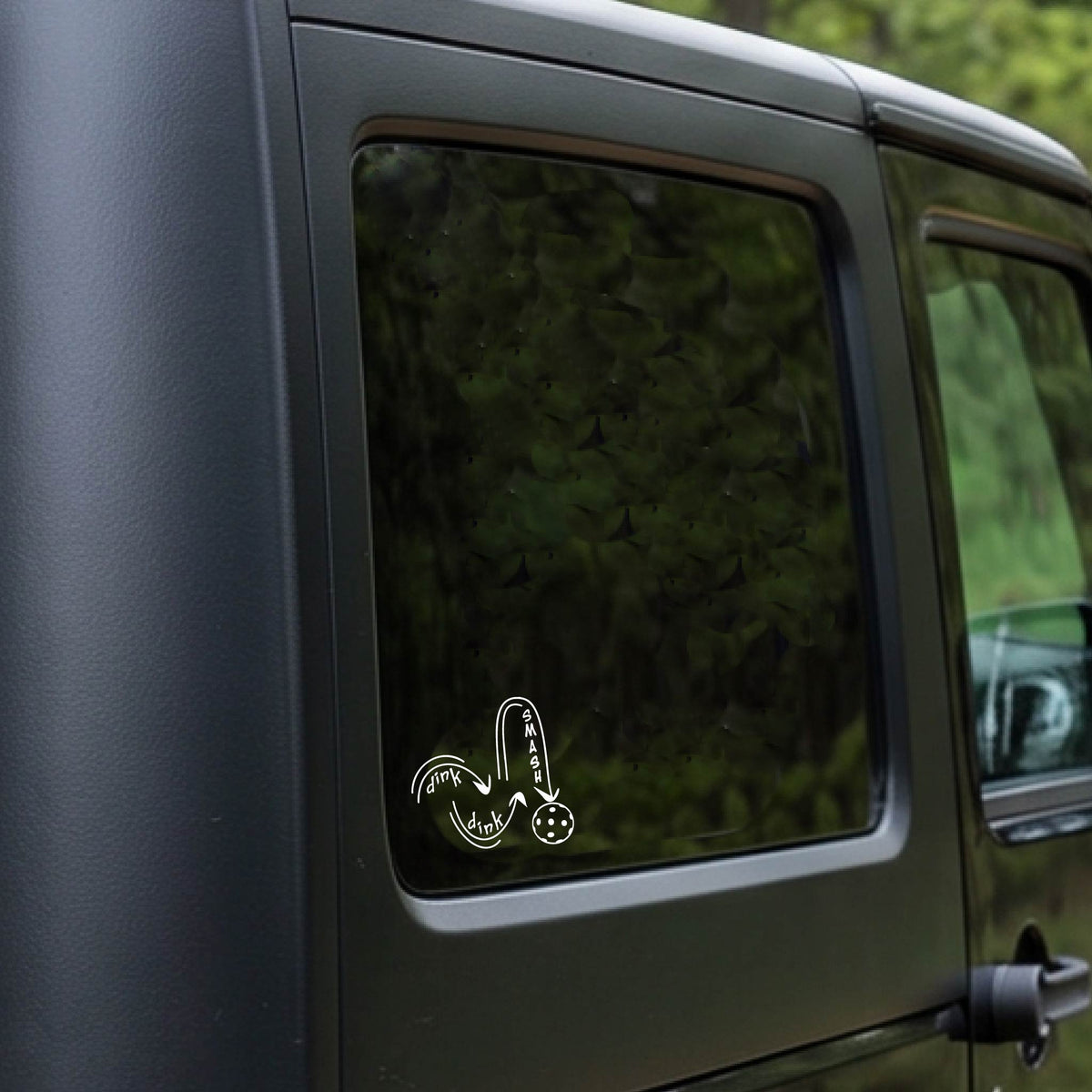 A white vinyl decal of a pickelball logo' DINK DINK SMASH' an a yellow pickleball, applied a vehicle window. 