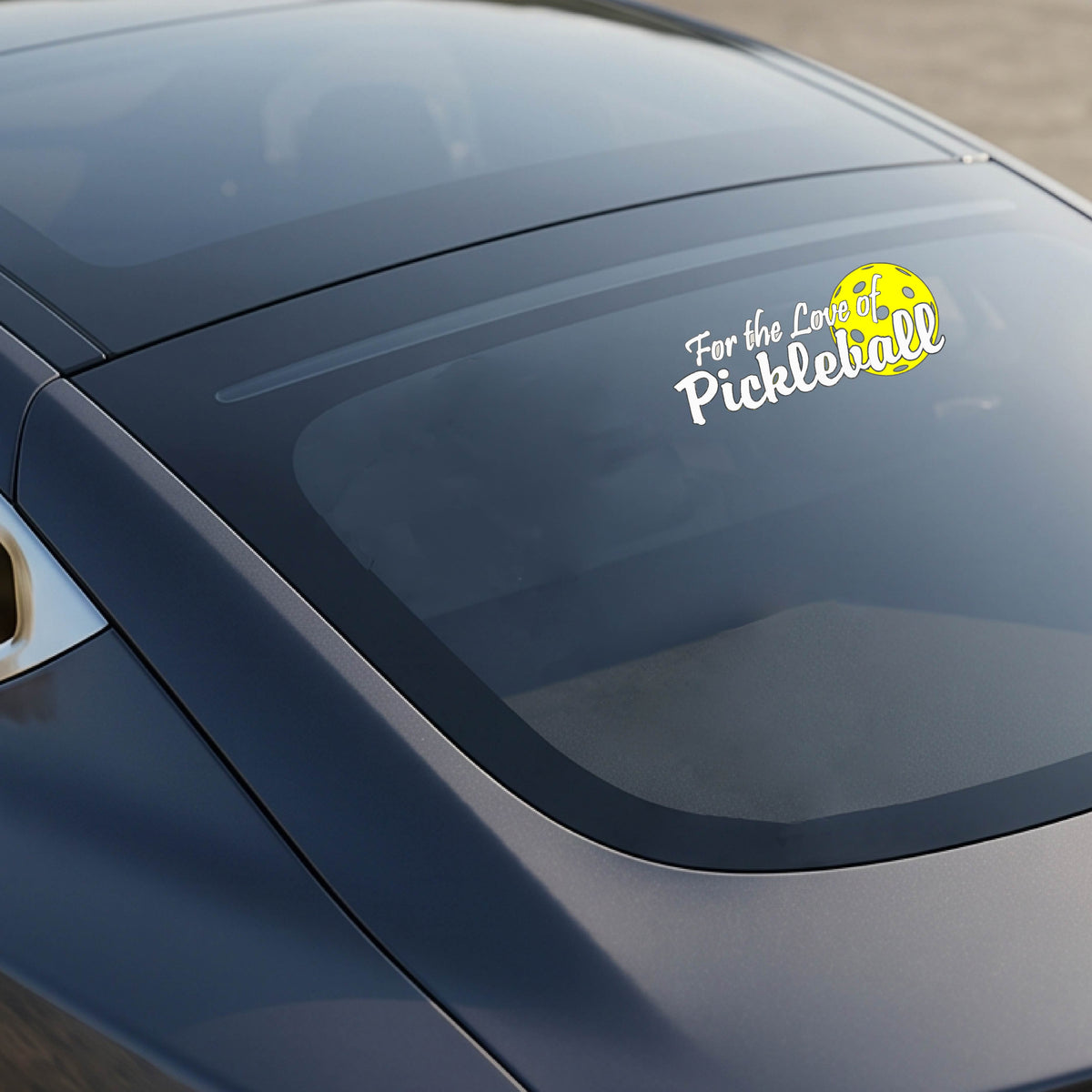 A close-up of a car decal and a pickleball graphic of ‘FOR THE LOVE OF PICKLEBALL’ in white with a yellow pickleball behind it graphic on the front.
