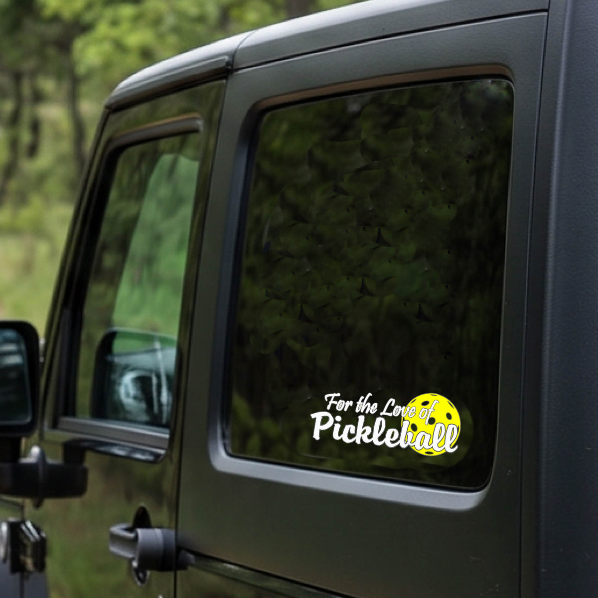A close-up of a car decal and a pickleball graphic of ‘FOR THE LOVE OF PICKLEBALL’ in white with a yellow pickleball behind it graphic on the front.