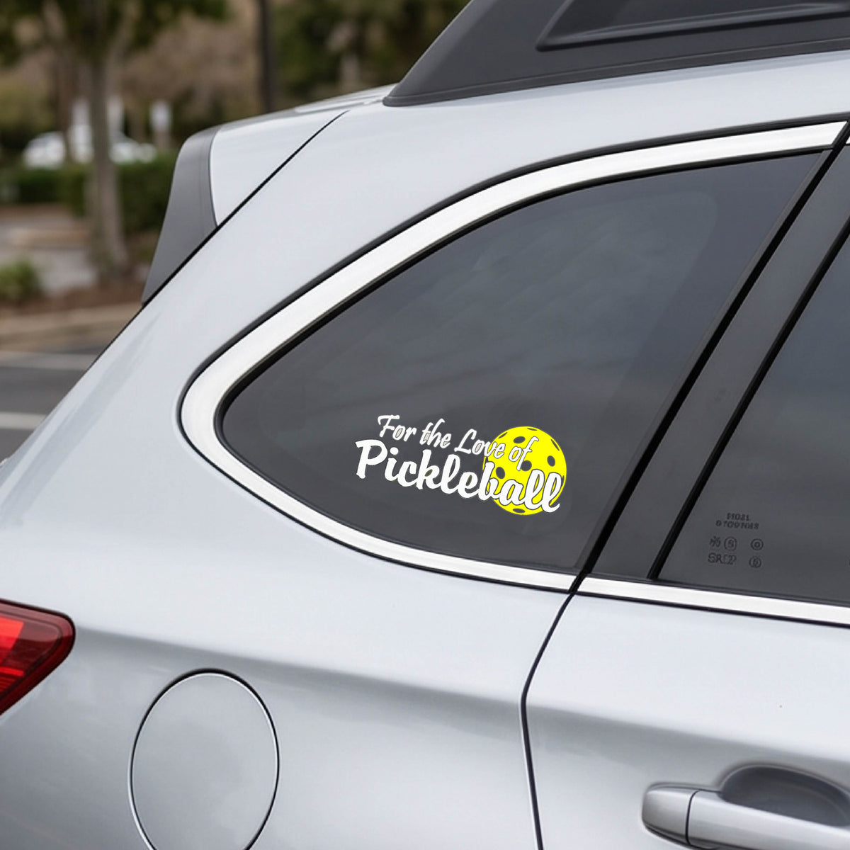A close-up of a car decal and a pickleball graphic of ‘FOR THE LOVE OF PICKLEBALL’ in white with a yellow pickleball behind it graphic on the front.