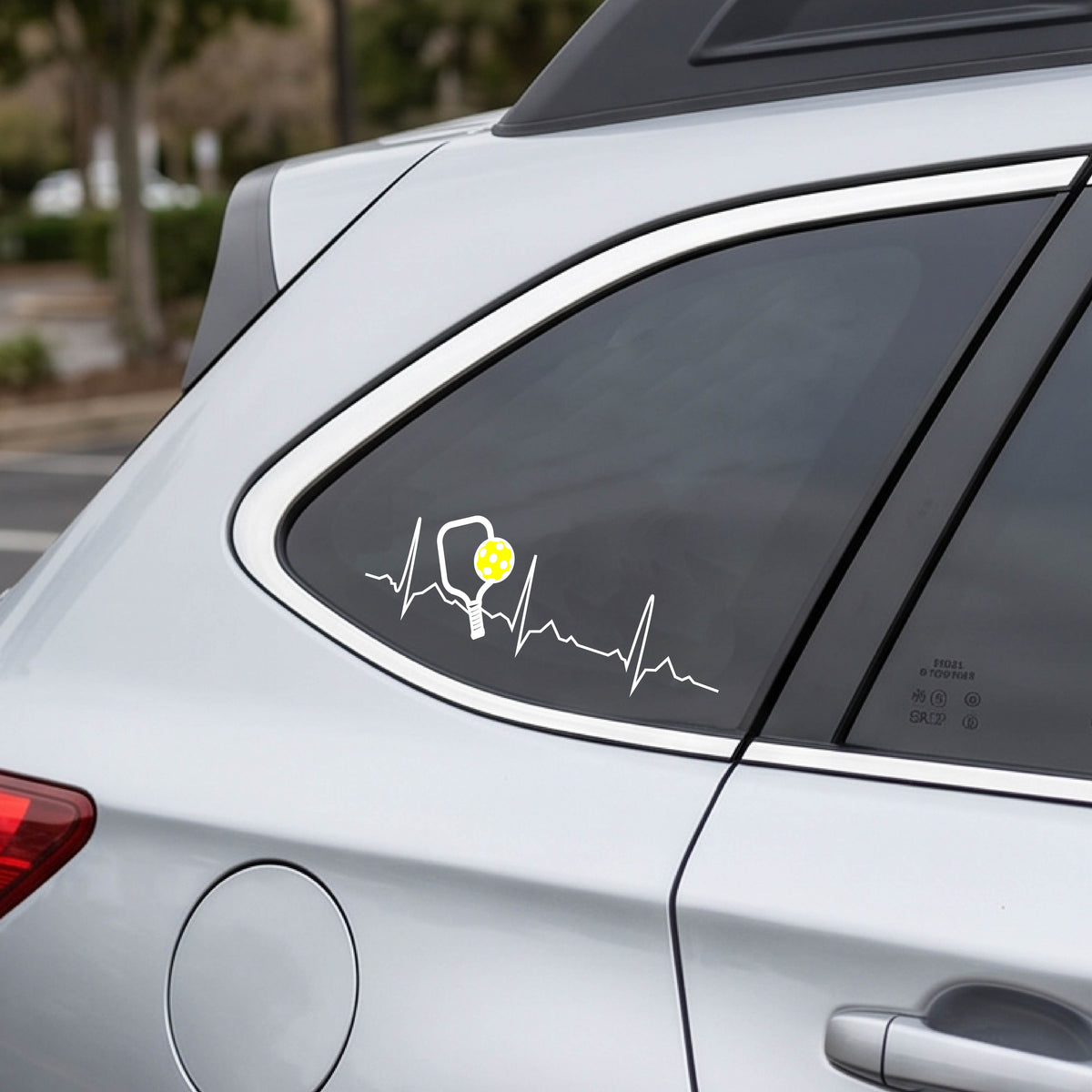 A close-up of a car decal showing a white pickleball graphic of a heartbeat EKG including a pickleball paddle and a yellow pickleball. 