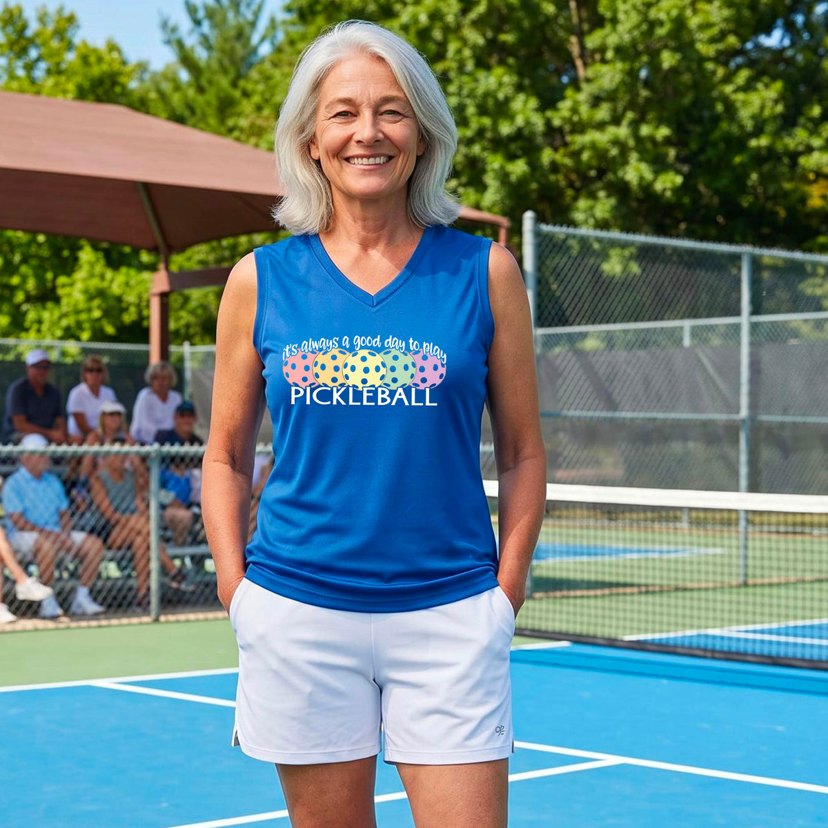 A woman smiling on a pickleball court, wearing a royal blue sleeveless tank top with a colorful pickleball graphic and the text 'it's always a good day to play PICKLEBALL'.