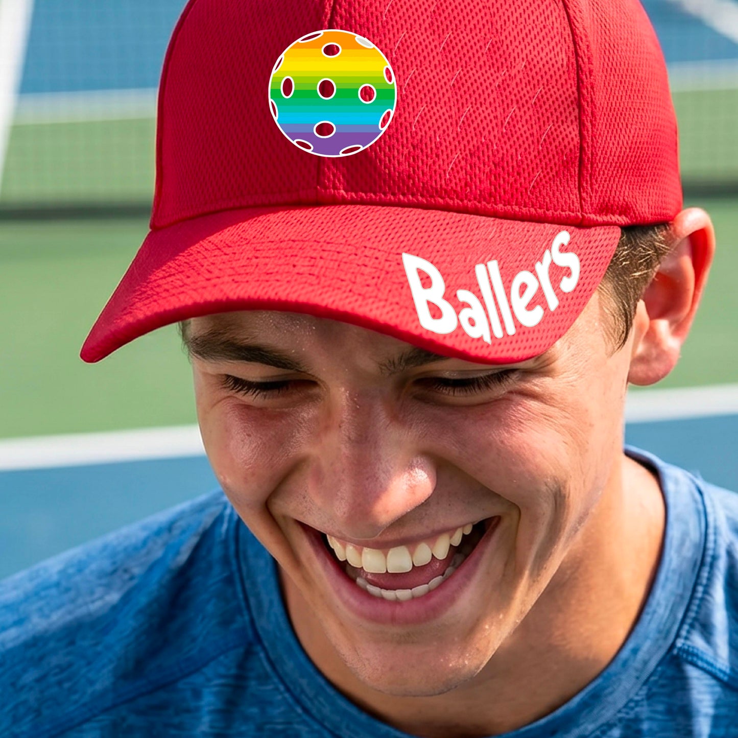A close up of a red baseball cap with a pickleball graphic on the front and the word 'Ballers' in white on the brim.