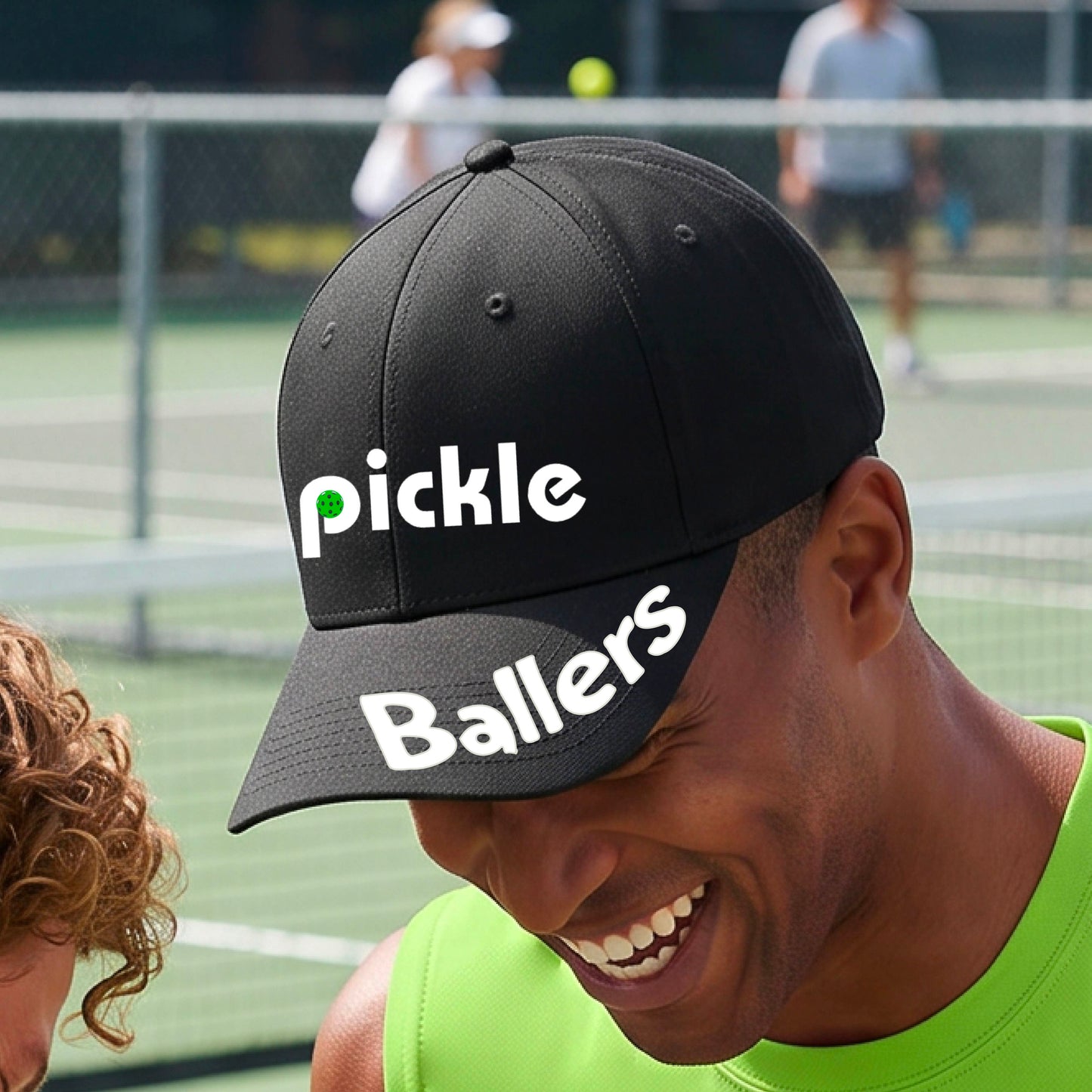 A close up of a black mid-profile pickleball baseball cap with the text 'pickle' across the front and 'ballers' curved on the brim. 