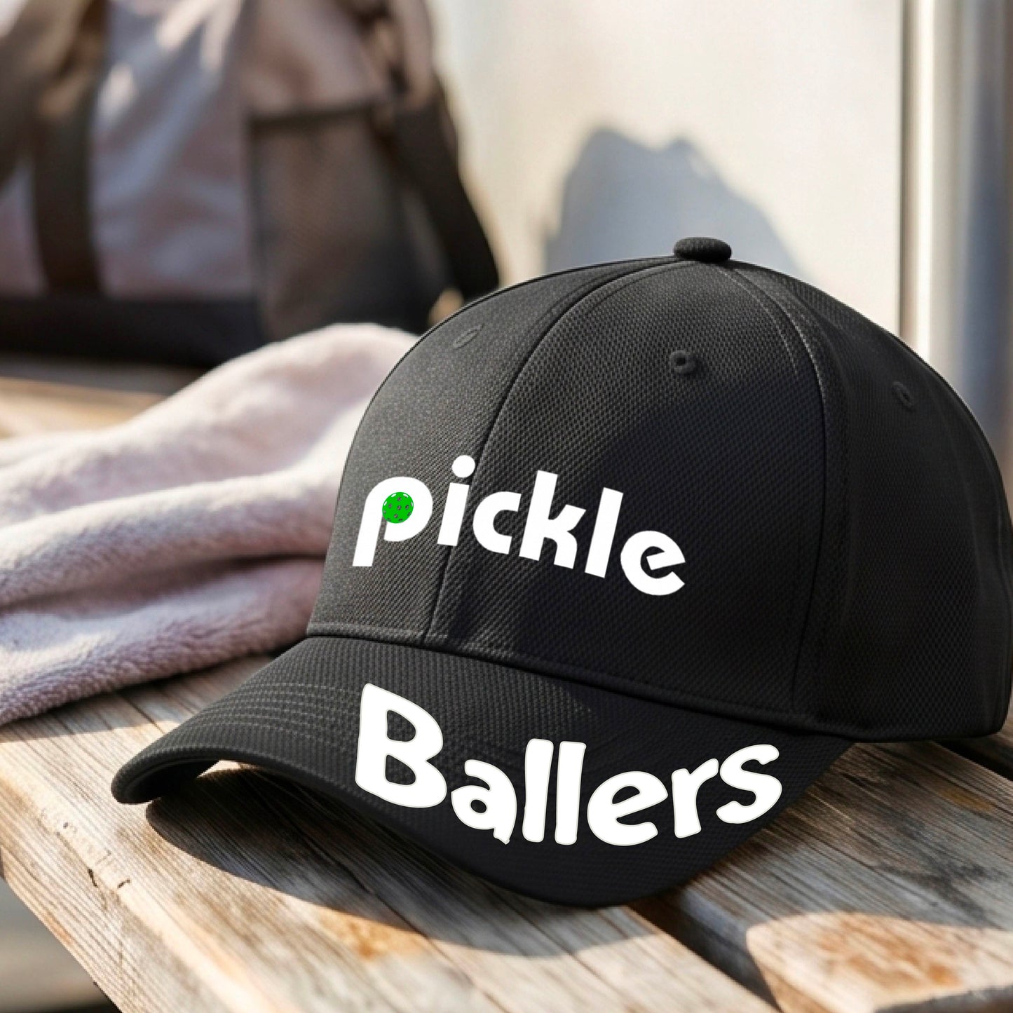 A close up of a black mid-profile pickleball baseball cap with the text 'pickle' across the front and 'ballers' curved on the brim. 