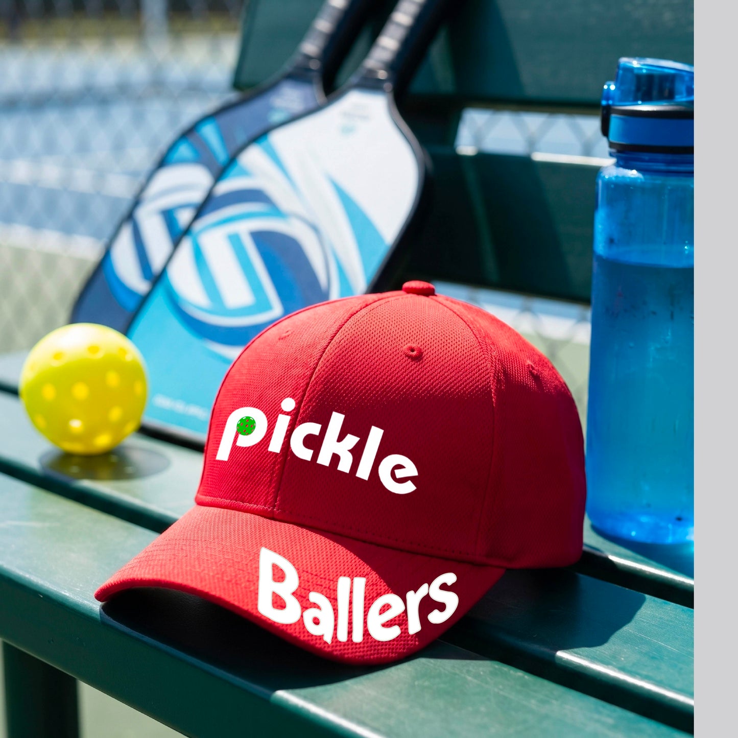 A close up of a red mid-profile pickleball baseball cap with the text 'pickle' across the front and 'ballers' curved on the brim. 