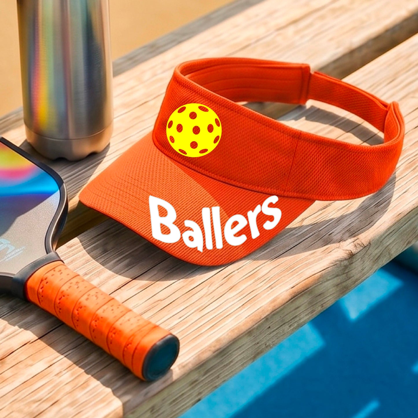 A close up of an orange visor with pickleball graphic and the word 'Ballers' in white,.