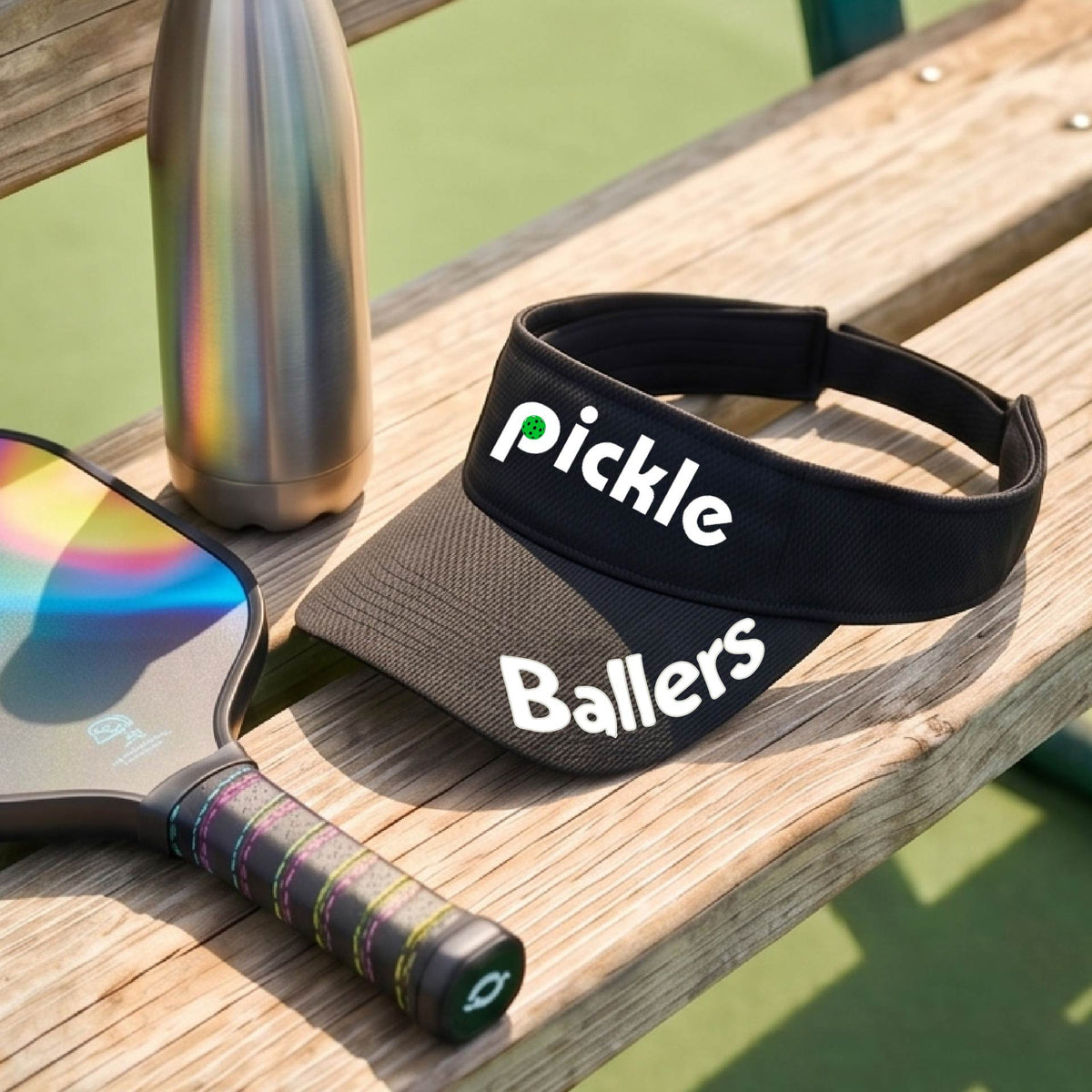 A close up of a black visor with a pickleball graphic of 'pickle' and 'Ballers' printed in white on the front and brim.