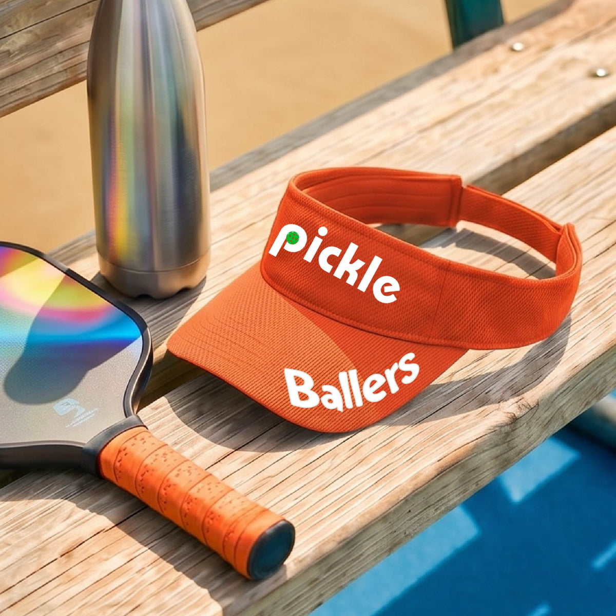 A close up of an orange visor with a pickleball graphic of 'pickle' and 'Ballers' printed in white on the front and brim.