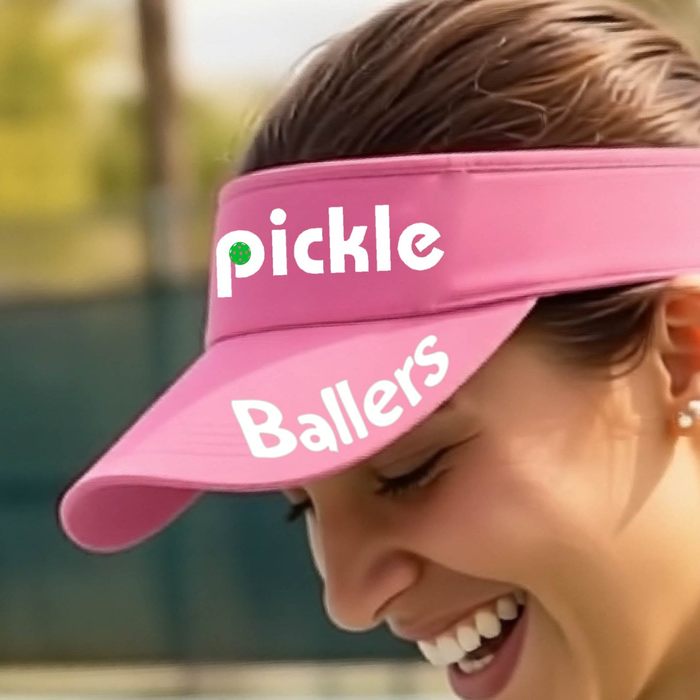 A close up of a pink visor with a pickleball graphic of 'pickle' and 'Ballers' printed in white on the front and brim.