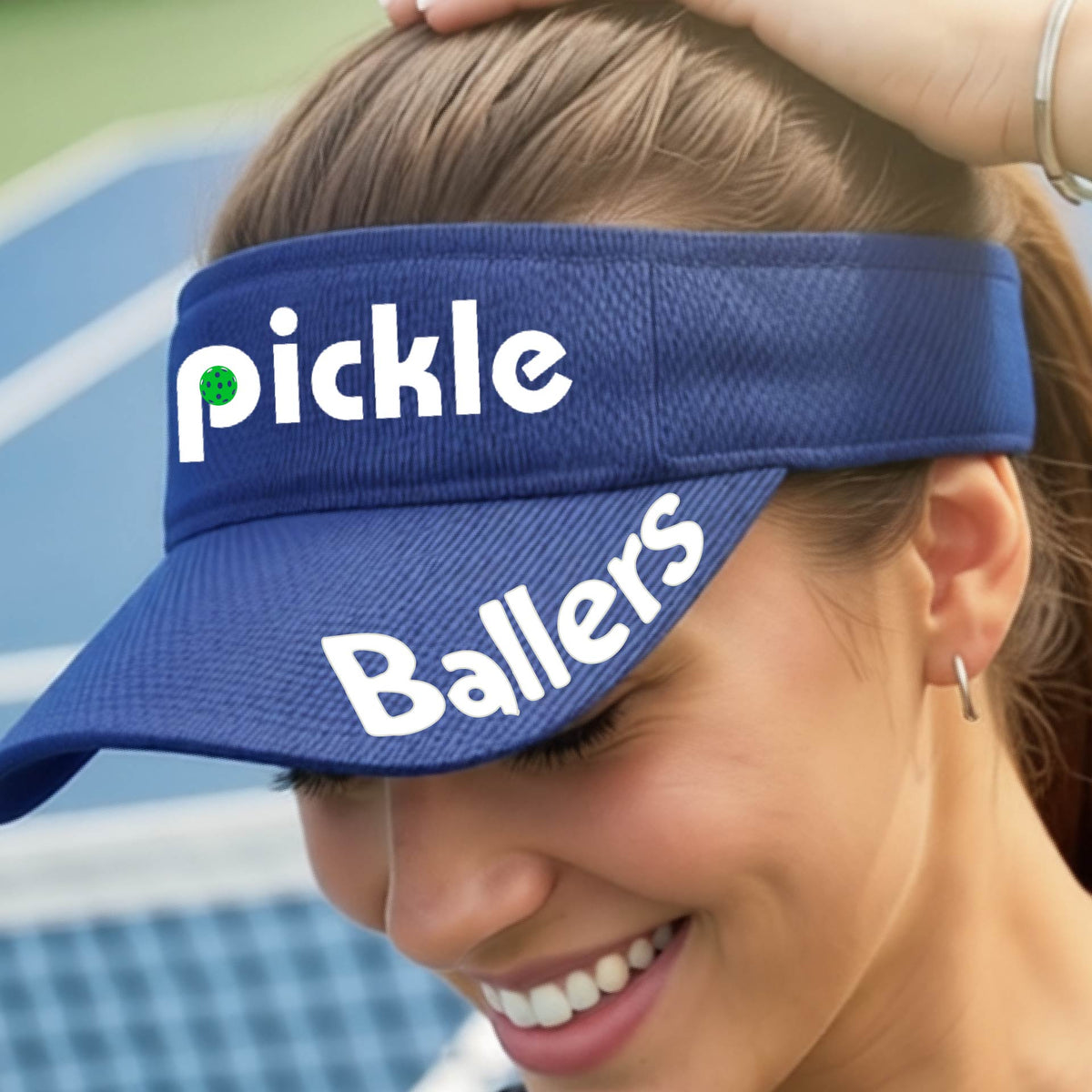 A close up of a royal blue visor with a pickleball graphic of 'pickle' and 'Ballers' printed in white on the front and brim.