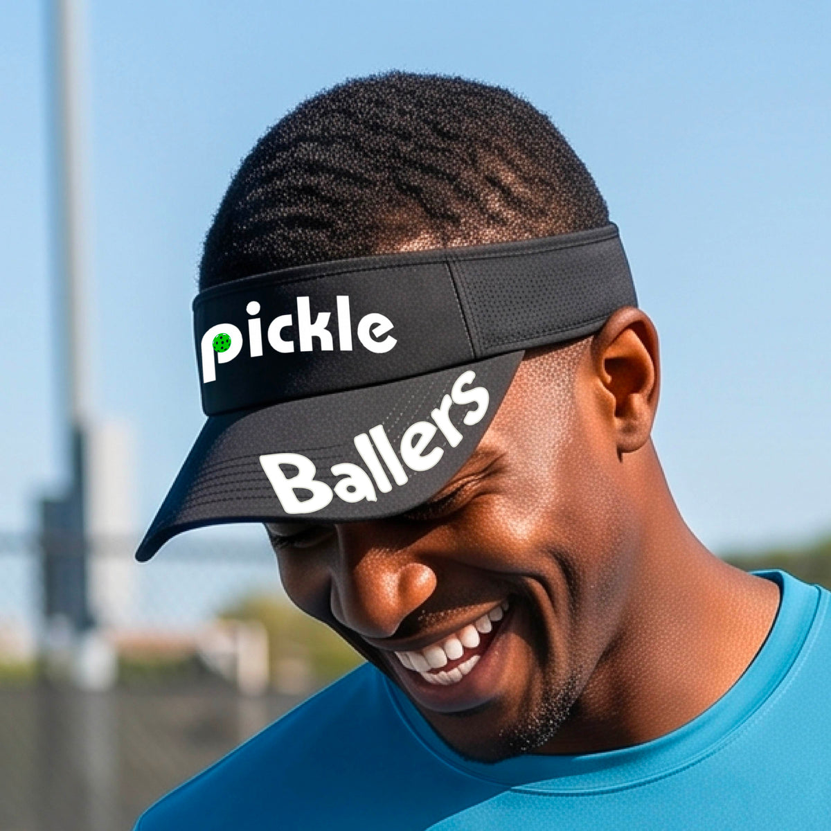 A close up of a black visor with a pickleball graphic of 'pickle' and 'Ballers' printed in white on the front and brim.