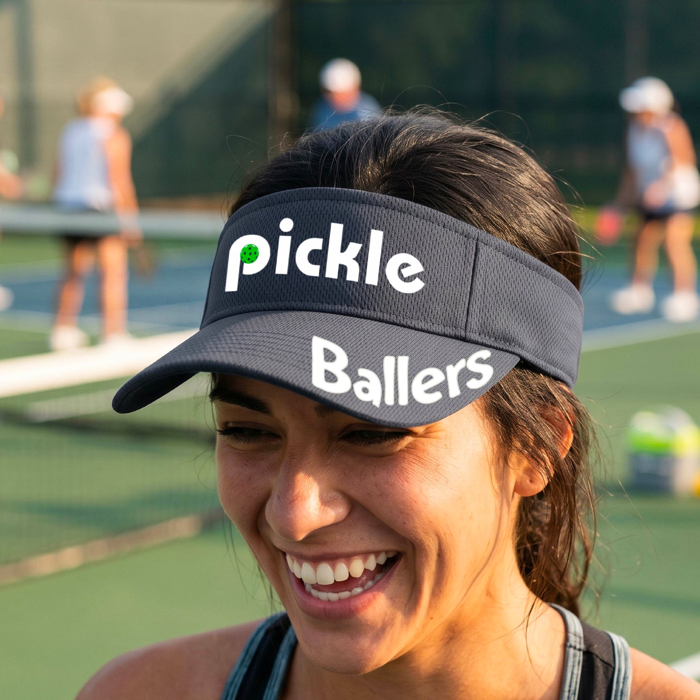 A close up of a graphite gray visor with a pickleball graphic of 'pickle' and 'Ballers' printed in white on the front and brim.