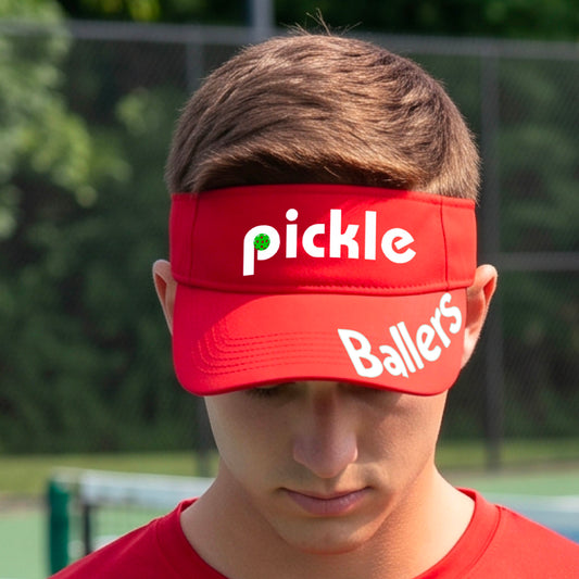 A close up of a red visor with a pickleball graphic of 'pickle' and 'Ballers' printed in white on the front and brim.