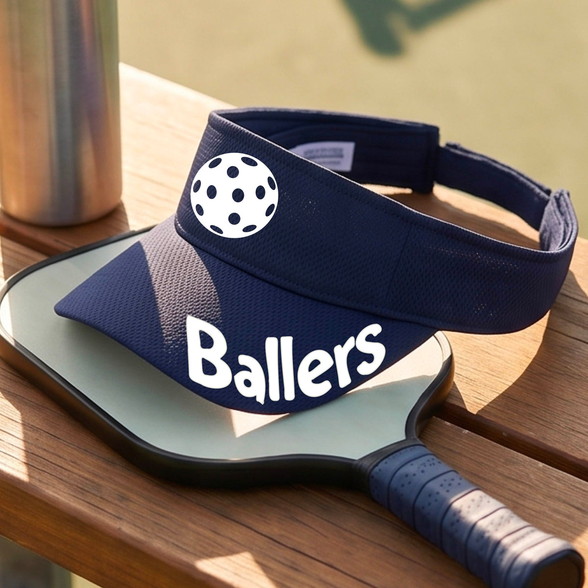 A close up of a navy blue visor with pickleball graphic and the word 'Ballers' in white,.