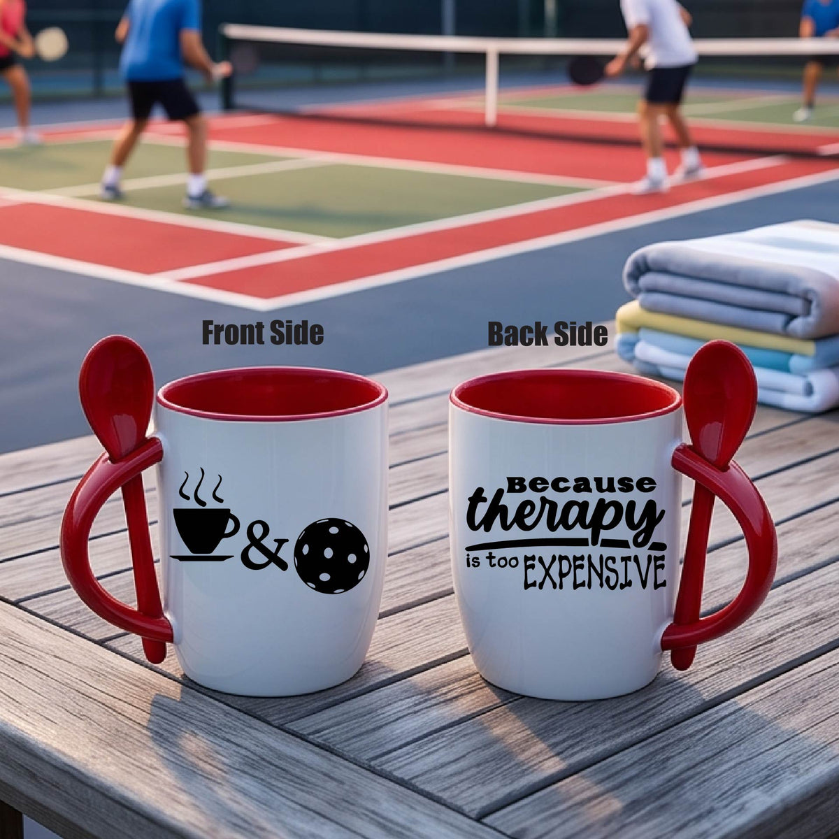 Alt Text:
a white and RED 12 ounce coffee mug with a built in spoon in the handle with and a fun coffee cup pickleball graphic and wraparound text 'BECAUSE THERAPY IS TOO EXPENSIVE" 
