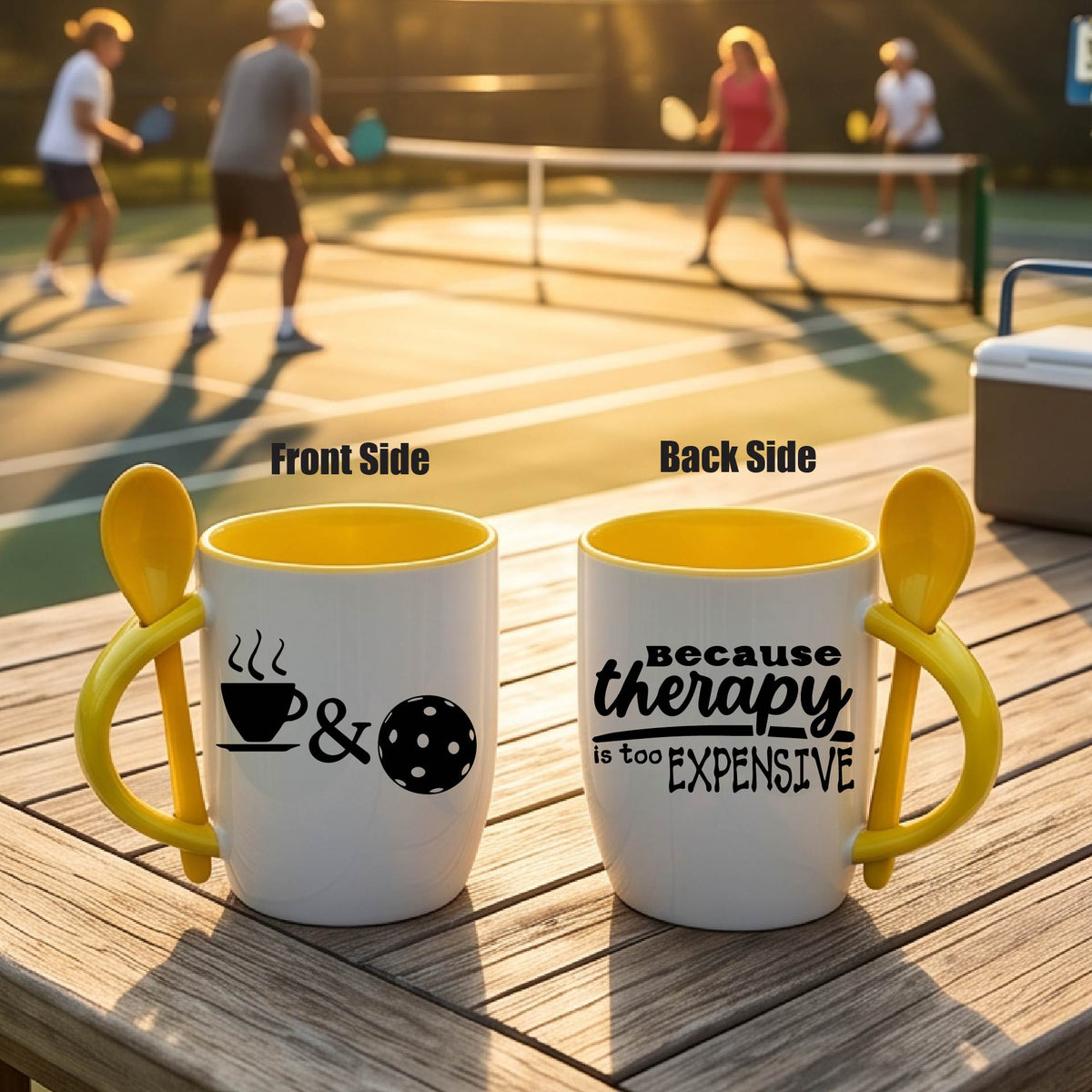 Alt Text:
a white and yellow 12 ounce coffee mug with a built in spoon in the handle with and a fun coffee cup pickleball graphic and wraparound text 'BECAUSE THERAPY IS TOO EXPENSIVE" 
