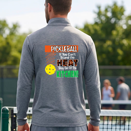 A man viewed from behind wearing a gray long-sleeve quarter-zip pullover with a colorful pickleball-themed graphic on the back. The graphic features the word 'PICKLEBALL' in orange, a yellow pickleball, and the text 'If You Can't Stand the HEAT Stay Out Of The KITCHEN!' in white and green.