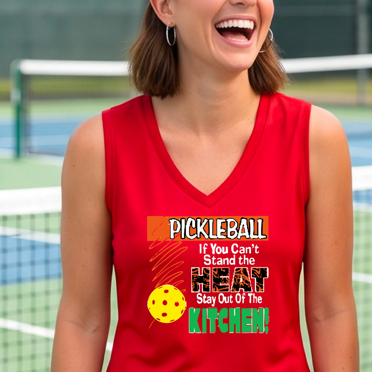 A close up of a red sleeveless V-neck tank top with a colorful pickleball graphic and text on the front "IF YOU CAN'T STAND THE HEAT STAY OUT OF THE KITCHEN."