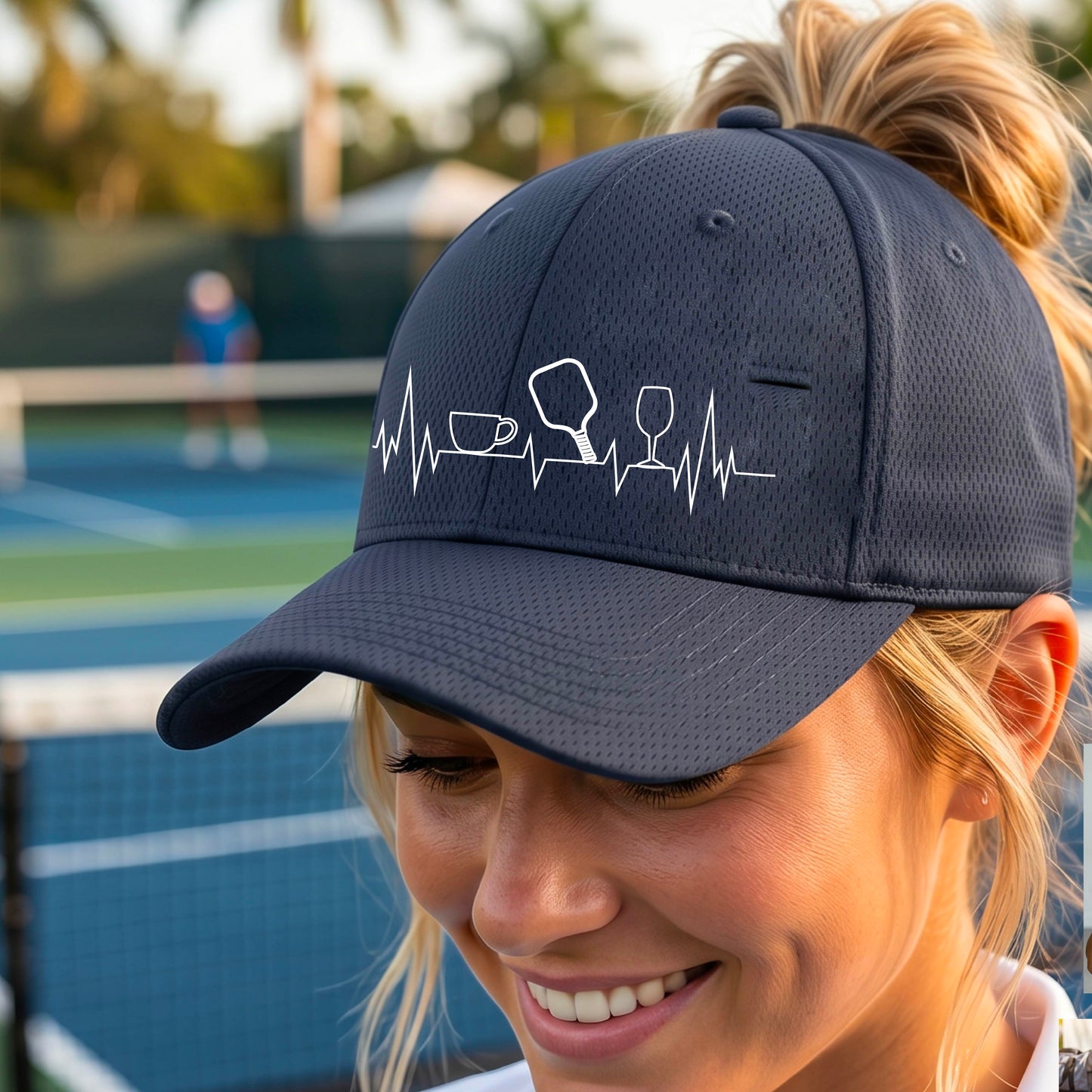 A close up of a navy blue  pickleball visor with  a white line-art graphic of a coffee cup, pickleball paddle and a wine glass, on a heartbeat EKG line.