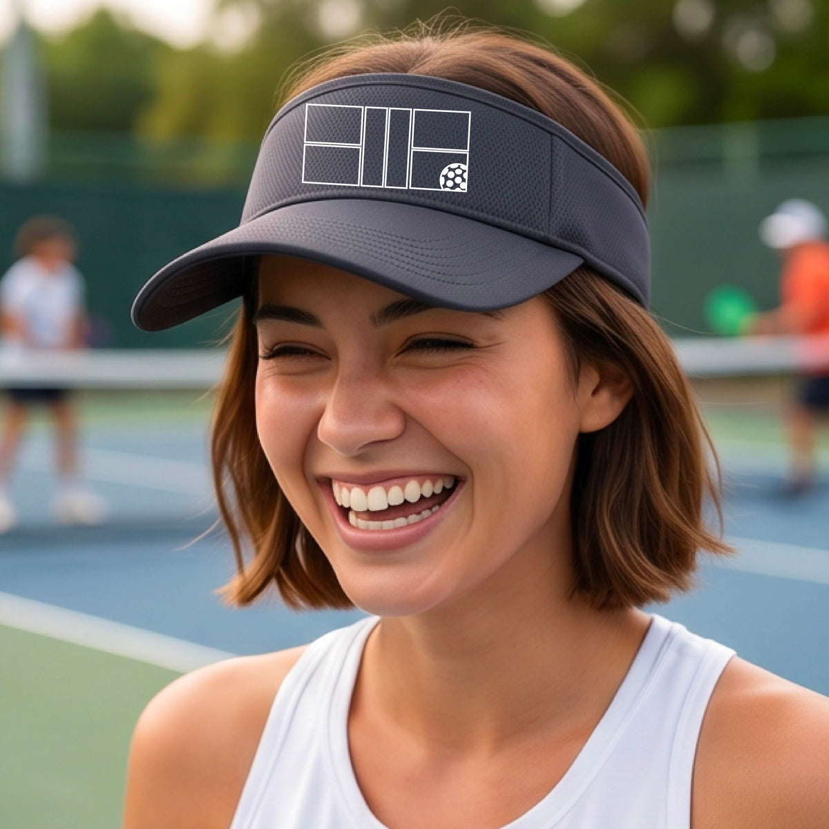 A close up of a gray visor with a white pickleball court and ball graphic on the front. 