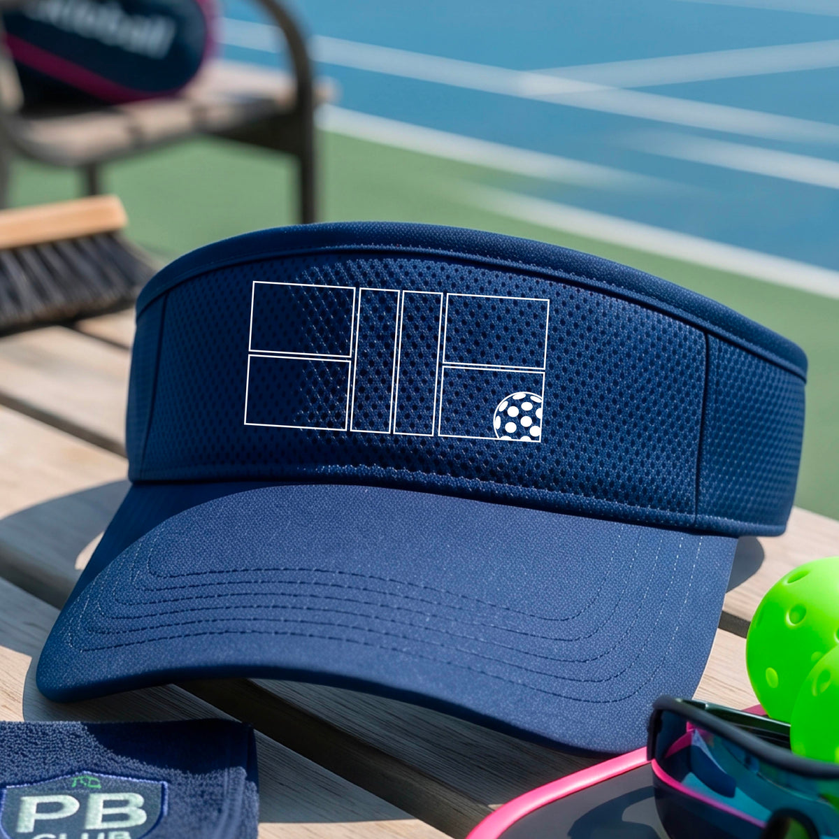 A close up of a royal blue visor with a white pickleball court and ball graphic on the front. 