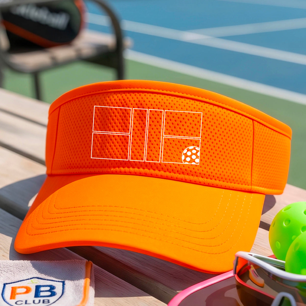 A close up of an orange visor with a white pickleball court and ball graphic on the front.