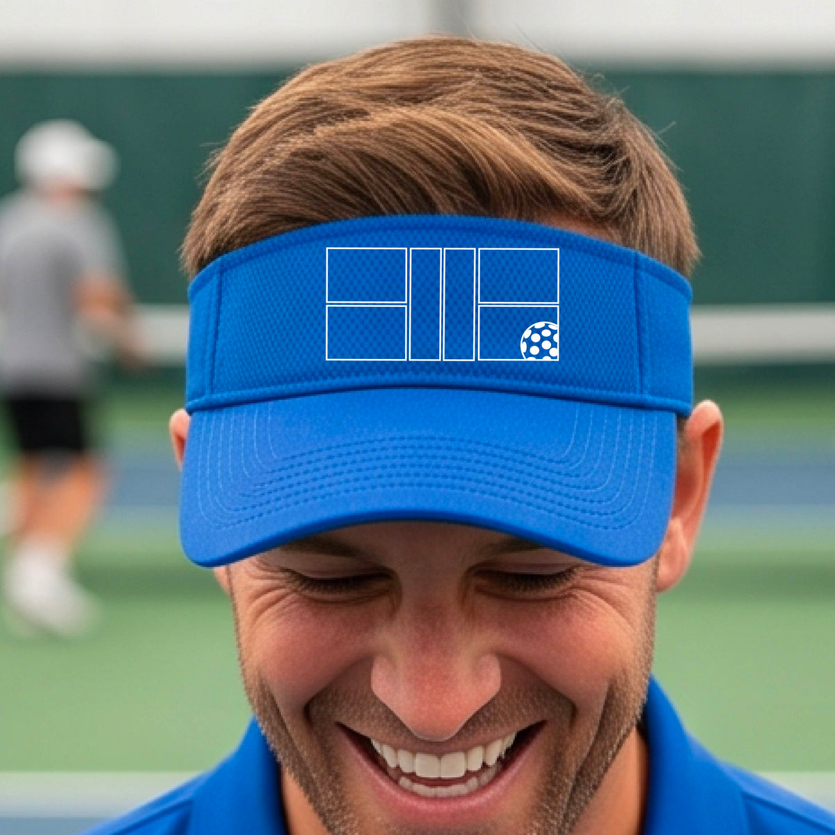 A close up of a royal blue visor with a white pickleball court and ball graphic on the front. 