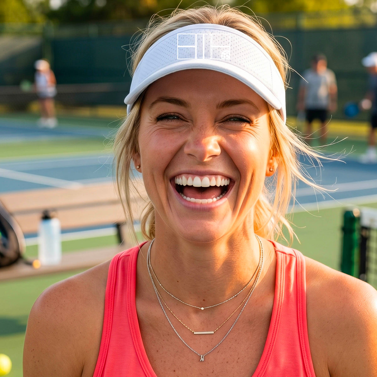 A close up of a white visor with a white pickleball court and ball graphic on the front. 