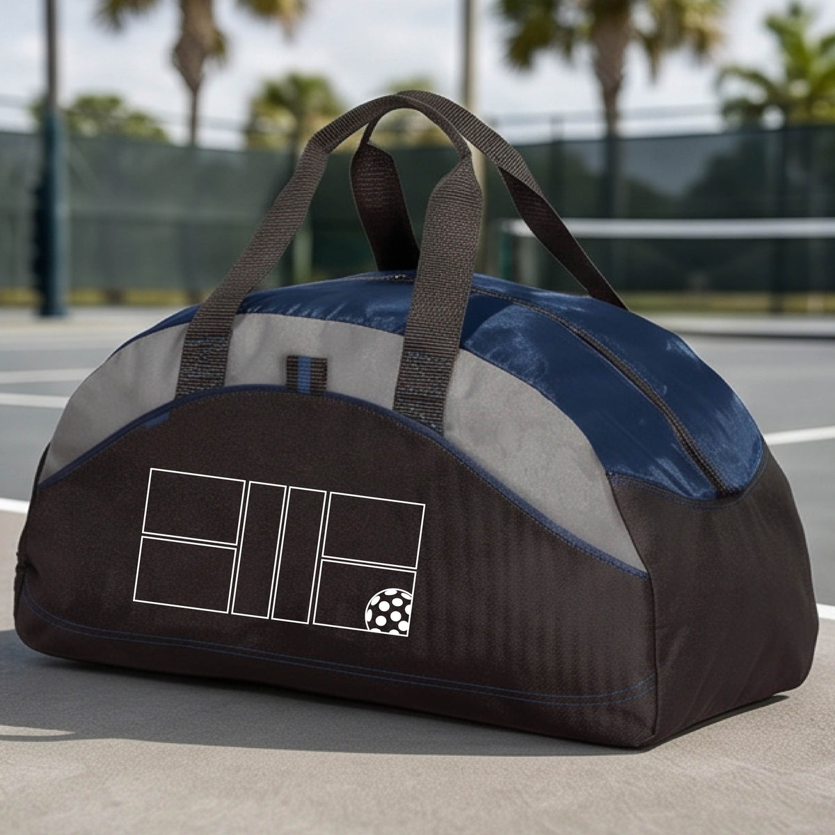 A close up of navy blue, gray and black pickleball duffel bag with a white pickleball court and ball graphic.